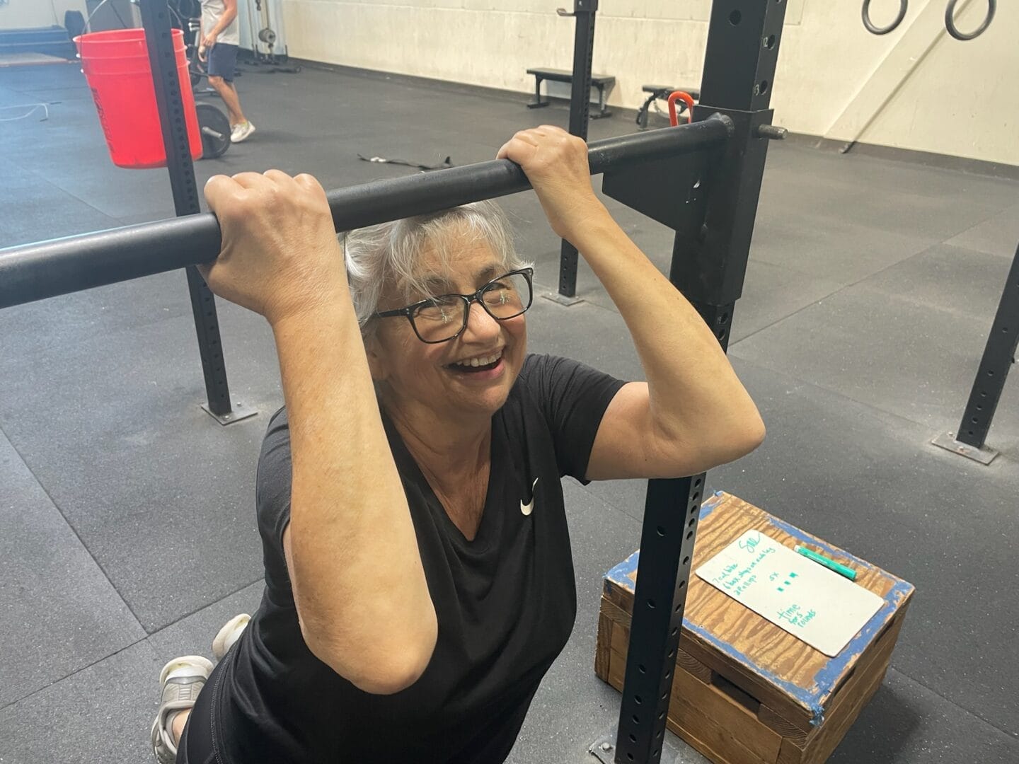 Masters gym member smiling completing a scaled pull-up.